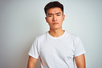 Young asian chinese man wearing t-shirt standing over isolated white background looking sleepy and tired, exhausted for fatigue and hangover, lazy eyes in the morning.