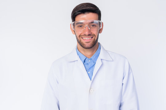 Happy young bearded Persian man doctor as scientist smiling