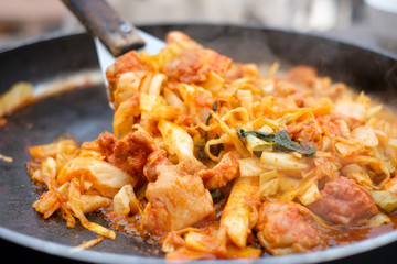 Close up fried Korean food called “Dakgalbi”with spade of frying pan,it's Korean style Chicken with spicy plate.The Korean favorite food which is chicken stir with spicy sauce,vegetable in big hot pan