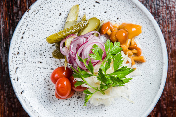 Traditional Russian appetizer and vodka, sauerkraut with cranberries, herring, pickled cucumbers, pickled mushrooms and tomatoes.