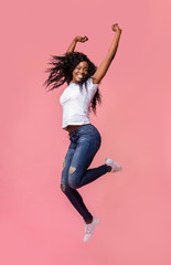 Smiling young african woman jumping in air