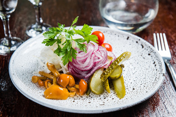 Traditional Russian appetizer and vodka, sauerkraut with cranberries, herring, pickled cucumbers, pickled mushrooms and tomatoes.