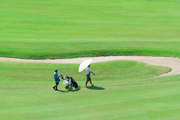 Golfers go on a green golf course.