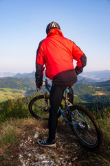 Fototapeta na wymiar Velky Lipnik, Pieniny National Park, Slovakia-July 2019: Cyclist observing the landscape from the top of the mountain