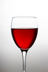 Wineglass with red wine close-up isolated on light gradient background