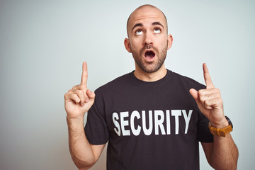 Young safeguard man wearing security uniform over isolated background amazed and surprised looking...