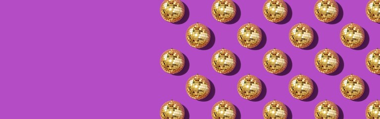 Creative Christmas pattern. Shiny gold disco balls over violet background. Flat lay, top view. New year baubles, star sparkles. Party time. Cristmas greeting card