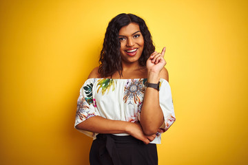 Transsexual transgender woman wearing summer t-shirt over isolated yellow background with a big smile on face, pointing with hand and finger to the side looking at the camera.