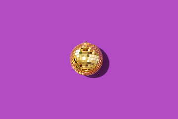 Gold mirror disco ball on violet background. Flat lay, top view. Minimal New year party concept. Christmas greeting card with copy space