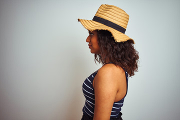 Beautiful transsexual transgender woman wearing summer hat over isolated white background looking to side, relax profile pose with natural face with confident smile.