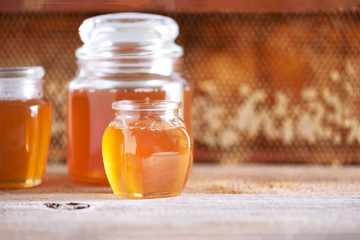 Honey products background. Honeycomb frame, bee pollen granules, honey in glass pot on grey concrete background. Copy space. Autumn harvest concept.