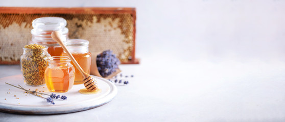Bee pollen granules, honey jar with wooden dropper, honeycomb on grey backdrop. Copy space. Autumn...