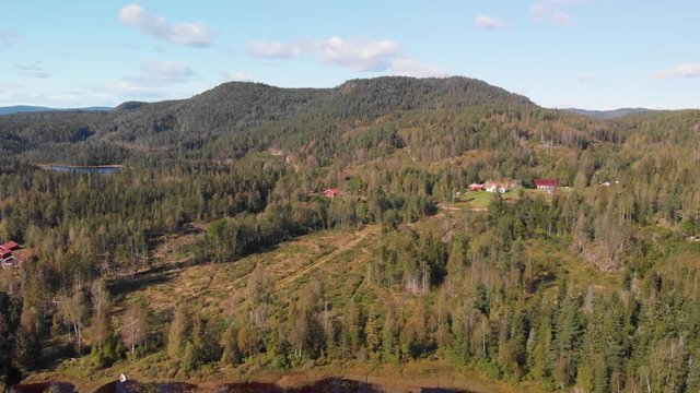 Aerial view over Heisetra cabins with a beautiful lake and lots of pine trees and forest surrounding the cabins, in Kodal, Norway