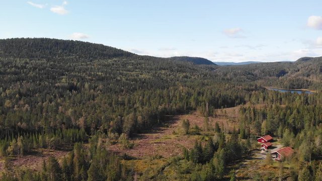 Aerial view over Heisetra cabins with a small lake and lots of pine trees and forest surrounding the cabins, in Kodal, Norway