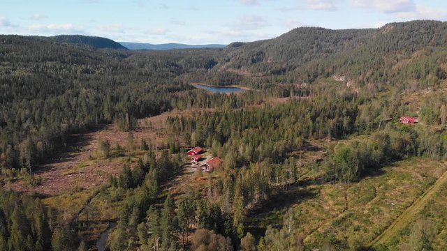 Aerial view over Heisetra cabins with a beautiful lake and lots of pine trees and forest surrounding the cabins, in Kodal, Norway