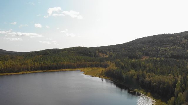 Aerial view over a beautiful still blue water lake surrounded by forest at Heisetra cabin in Kodal, Norway