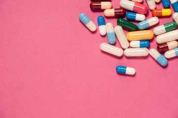 Different capsule pills on pink background. 