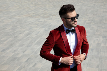thoughtful young man arranging red velvet tuxedo