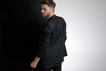 back view of smart casual man holding sunglasses in studio