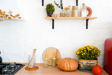 autumn kitchen interior with shelfs, yellow flowers and pumpkin