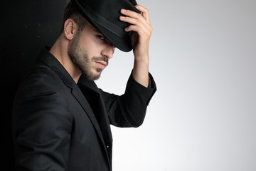 confident young man holding black hat in studio