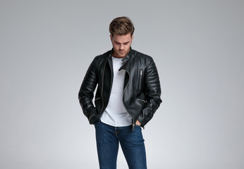 casual man standing with hands in pockets and looking down