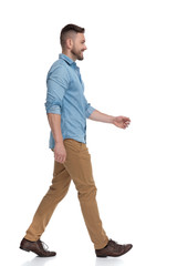 casual man with blue shirt walking and looking ahead happy