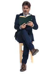businessman sitting and reading a book intrigued