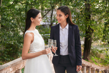 Beautiful lesbian couple with glasses of champagne on their wedding day outdoors