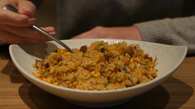 Bowl with freshly cooked fried rice with meat, closeup shot, woman take full spoon of food. Closeup shot of meal served at Chinese restaurant