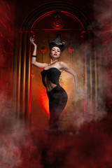 Evil stylish woman witch with big black hat on dark scary smoky background alone