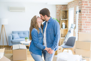 Young couple around cardboard boxes very happy moving to a new home