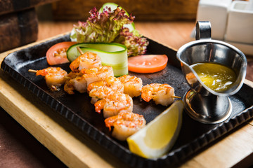 Grilled shish kebab with vegetables on black.