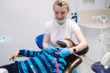 Little boy sitting in dentist in vr glasses and wireless headphones while dentist make x-ray of teeth. male patient
