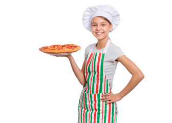 Happy beautiful teen girl in chef hat holding cooked pizza. Girl cook in apron holds plate with fresh pizza, isolated on white background. Portrait of cute child showing delicious Italian pizza.