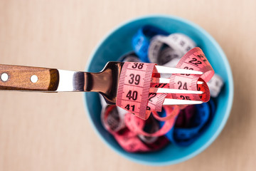 Many colorful measuring tapes in bowl on table