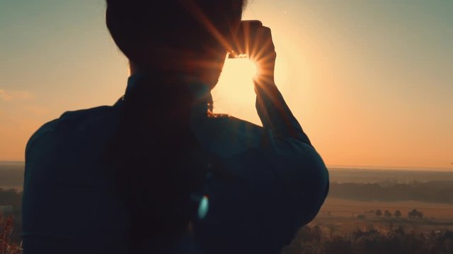 close up back view of woman take phone holding smartphone at sunrise warm sunlight traveller at vacation
