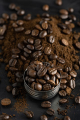 Coffee beans on Metal portafilter or Filter Holderand  and ground powder on black marble background. Top view 