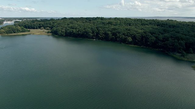 a shot with my drone mavic 2 zoon to a lake with trees and the city on the horizon and the beach