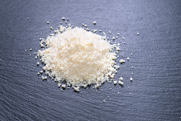 fresh grated cheese parmigiano on black slate background