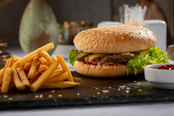 Burger and french fries with sauce on slate