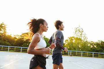 Photo of multinational slim couple running together