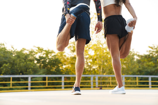 Cropped photo of strong couple stretching their legs together