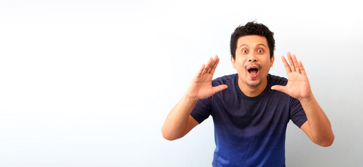 Portrait of Asian guy yelling, screaming, shouting, hand on his mouth, on White background copy space.