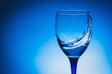 wine glass of flying water on blue background