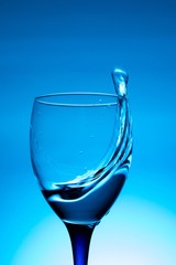 wine glass of flying water on blue background