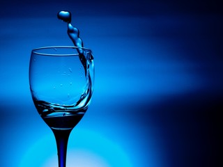 wine glass of flying water on blue background