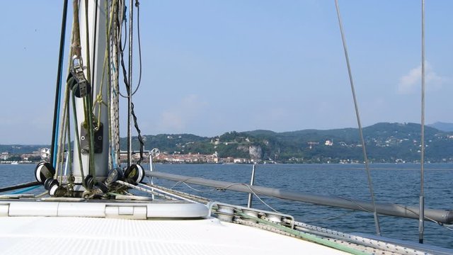 Base of the main mast of a sailboat with panorama between Arona and Angera area on the lake Maggiore in the north of Italy as a background - Real Time in 4K