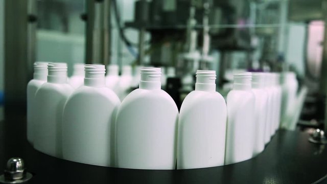 Cosmetics Manufacturing Plant. White Bottles On The Belt Conveyor. Shampoo