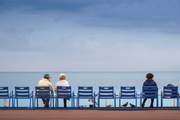 Couples sitting on the bank of the sea feeding pigeons and seagulls.